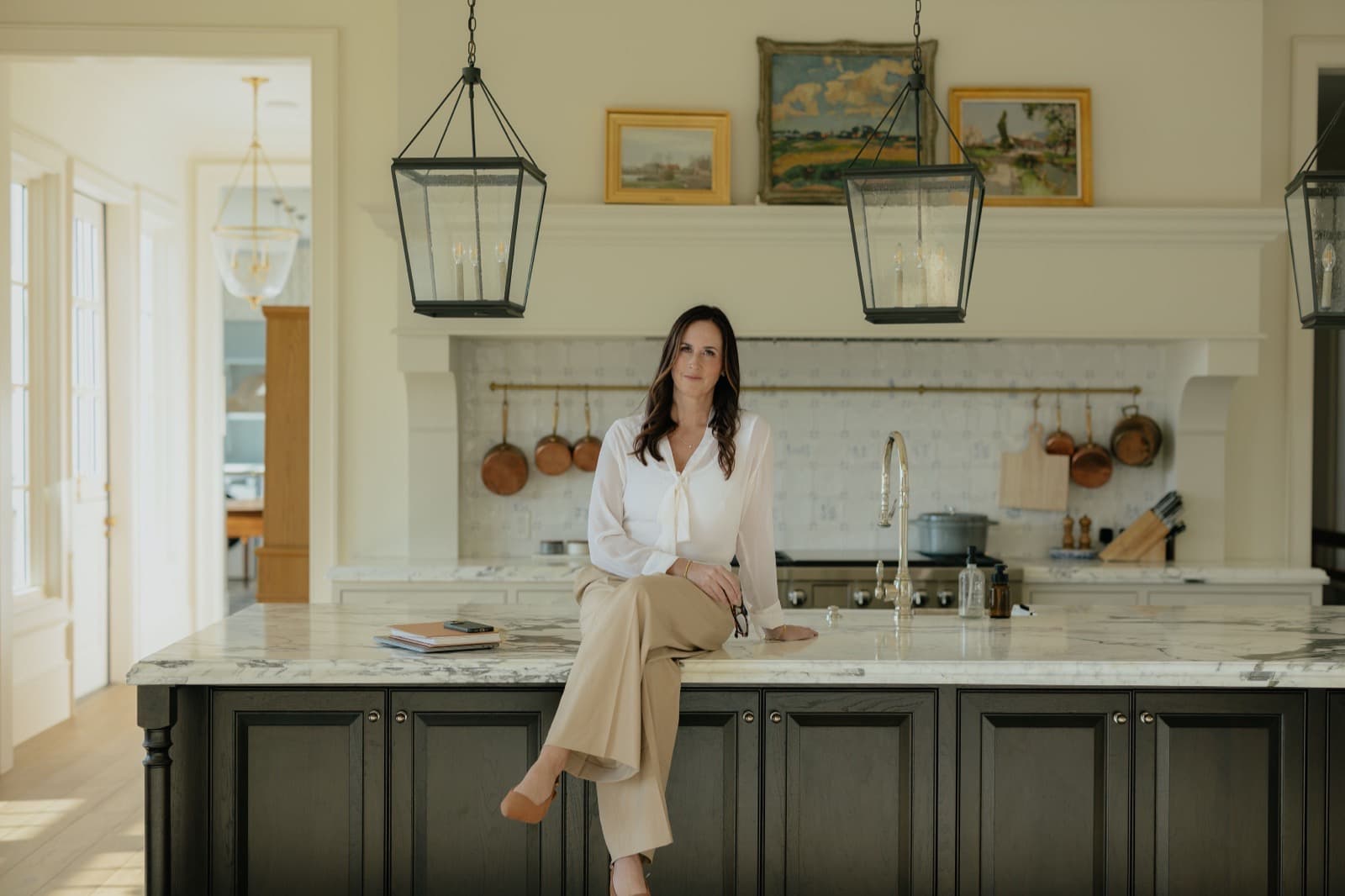 Nicki Christensen sitting on marble kitchen island in luxury Utah home